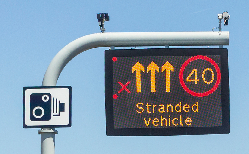 Motorway gantry sign showing a red X over the left lane, amber arrows over the other lanes, a red 40 mph limit and the words 'Stranded vehicle'